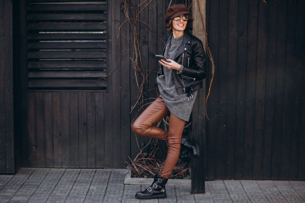 Young beautiful woman talking on the phone outside in faux leather pants